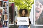 Love Island star Amber Gill, standing between rows of photos of people who have taken their own lives, holding a sign saying '125 lives are lost every week to suicide'