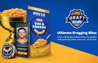 Trophy filled with Kraft Mac & Cheese next to smart phone displaying pictured of Tucker Kraft, ring that reads "The Big Cheese" and box labeled "85'er; Kraft Yac & Cheese"