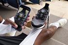 Someone holding Adidas trainers with a QR code on them and scanning the QR code on their phone