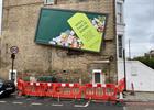 The Waitrose billboard tilted on a wall with fencing underneath (Image via X)