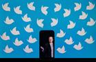 Image of Elon Musk on a device in front of a Twitter background. 