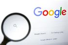 Magnifying glass held over computer screen displaying Google homepage