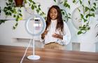 Black woman making a video blog with smartphone and ring light at studio. Influencer recording a video for his social media channel.