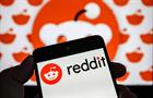 Hand holding smartphone displaying Reddit logo