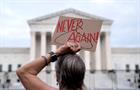 Pro-choice demonstrator holds a "NEVER AGAIN" sign outside the Supreme Court