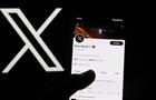 The X logo next to Elon Musk's Twitter account on a phone screen.