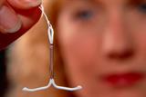 A woman holds an intrauterine contraceptive device (IUD), or coil (SPL)