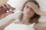 Woman taking her temperature with a thermometer