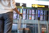 Woman with suitcase in front of departure board at airport