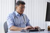 Male GP using a computer