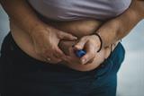 Overweight woman injecting himself in stomach