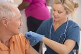 Nurse giving elderly man the flu vaccination