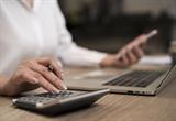 Person typing on computer and using calculator