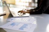 Person looking at computer, with charts on table