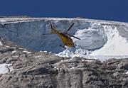 A rescue helicopter flies over the Punta Rocca glacier that collapsed on the mountain of Marmolada, after a record-high temperature of 10°C was recorded at the summit. July 2022. Photo: TIZIANA FABI/AFP via Getty Images