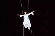 A peformer hangs from a contruction crane