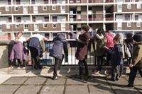 Children leaning on railing in front of a block of flats