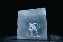 The outline of a man stands inside an ice cube, he is crouched down in a position which looks like he is ice skating.