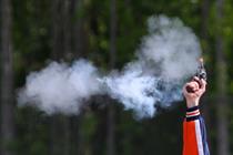 Image of race starter's pistol. with smoke trailing from the firing cap