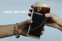 A still from the ad showing a pint of Guinness being passed from one hand to another
