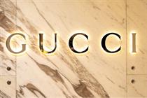 A golden Gucci logo against a marble background