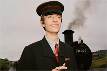 Francis Bourgeois, the viral TikTok star, in a film for Gucci, standing in a train guard's uniform on a station platform