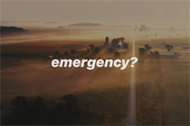 A still from Apple Watch's latest ad '911' showing a brown rural landscape and the word 'emergency?' superimposed in white lettering