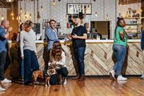 People standing around in the office looking happy with a dog
