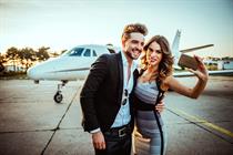 a glamorous couple takes a selfie in front of a jet