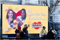 A van has text on that says "Here for the drama" and an image of two people eating popcorn with surprised expressions