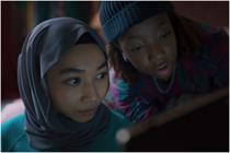 Two young people look intrigued while watching a laptop screen