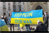 Group holding a banner of the Ukraine flag that says stop putin stop war
