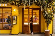Exterior shot of the Bumble Brew Cafe featuring yellow bricks and floral arrangements 