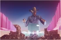 A motion-captured digital avatar of DJ Diplo performs above a digital city 