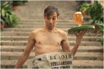 Naked man carrying tray of Stella Artois Unfiltered with a newspaper covering his lower half