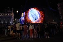 Image of space from the James Webb Space Telescope displayed on a video billboard to a crowd of onlookers