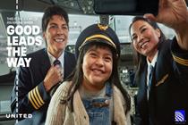 Smiling girl wearing an airplane captain's hat with pilot and copilot by her side