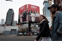 People walking past CNN+ billboard