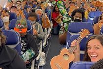 Crowded plane with passengers holding ukuleles