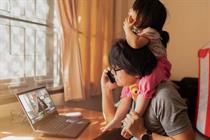 Parent working from home with child on shoulders