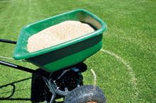 Fertiliser in a hand pushed spreader on a turf pitch
