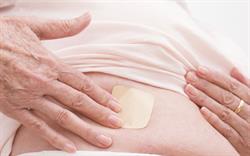 Woman applying a hormone patch to stomach. 