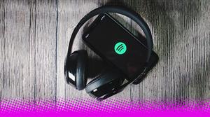 A pair of headphones on top of a smartphone showing the Spotify logo