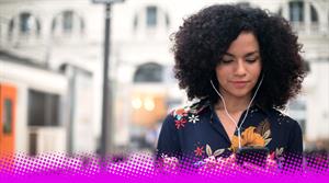 A photograph of a woman outside listening to headphones