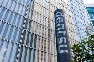 Dentsu logo in front of a glass building