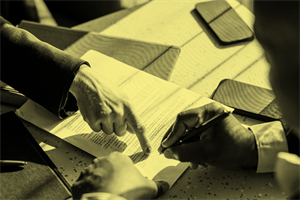 Close up of someone pointing to a document and someone else signing it