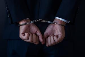 Man in a suit handcuffed. Photograph: Getty Images