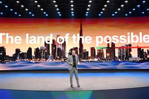 A man standing on a stage with a screen behind him showing a city skyline and text saying: The launch of the possible