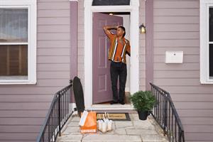A man standing on his porch with a Grubhub delivery in front of him