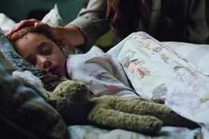 A girl asleep with a woman stroking her head